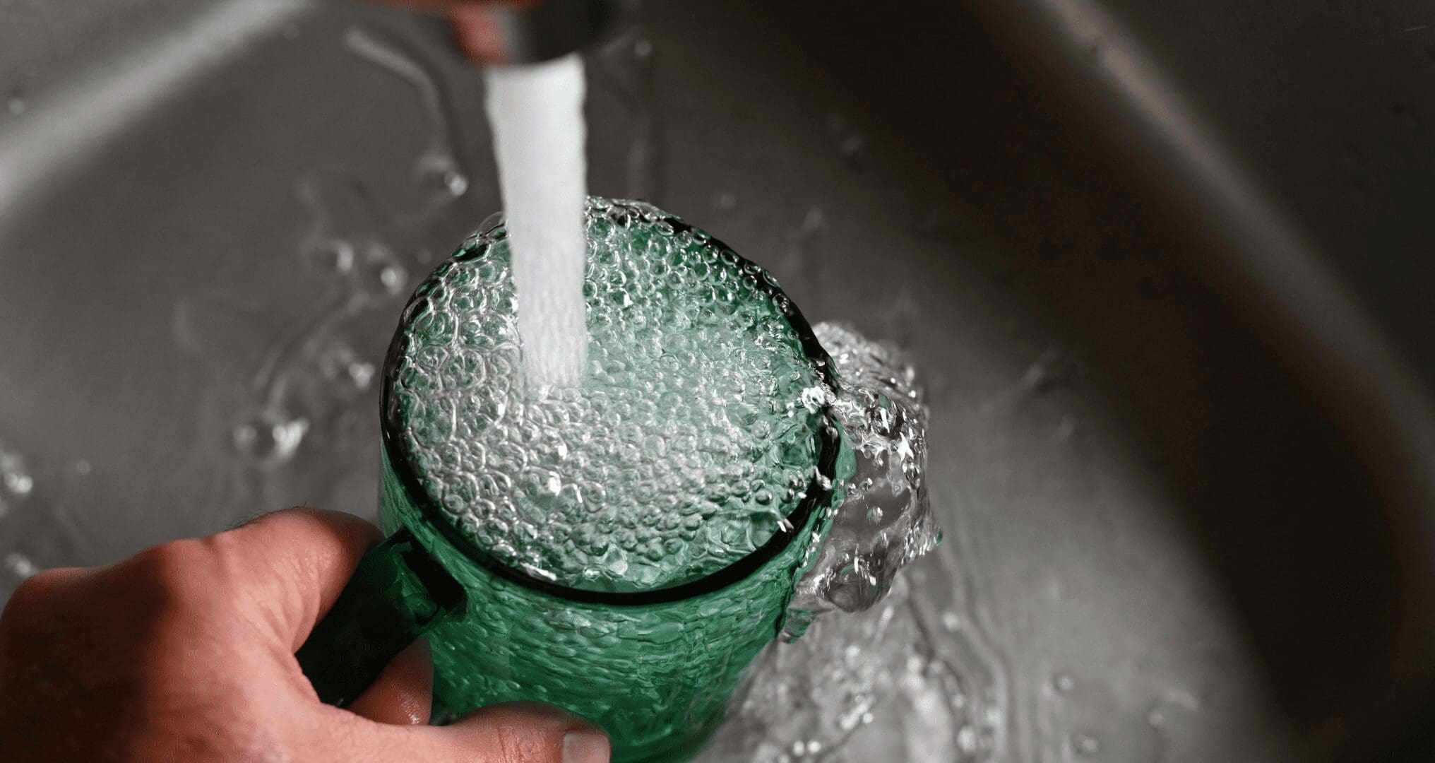 A person getting tap water from a home smart faucet