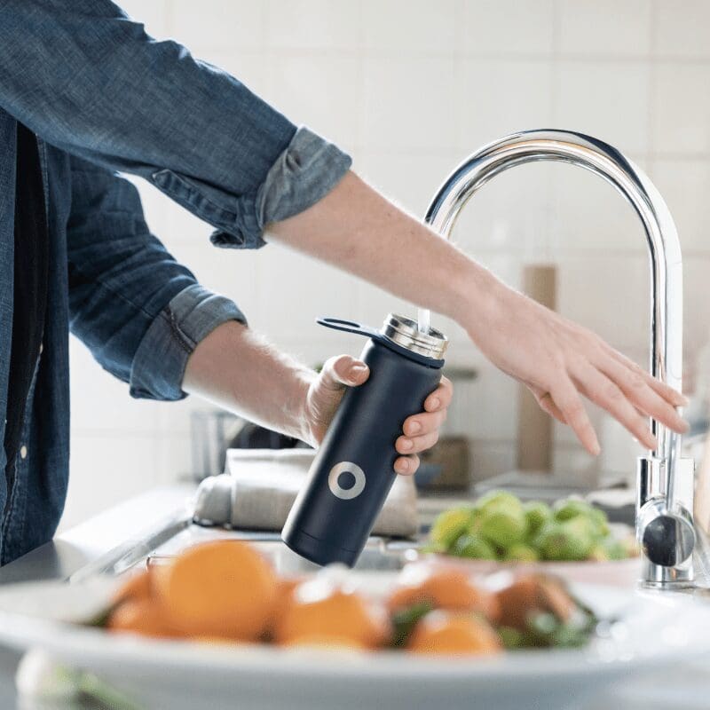 A person refilling his water bottle with cold water from a premium designer faucet