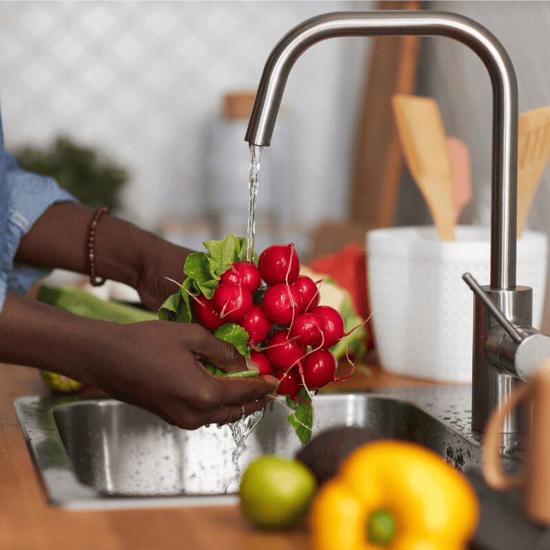 man washing vegetables under tap water