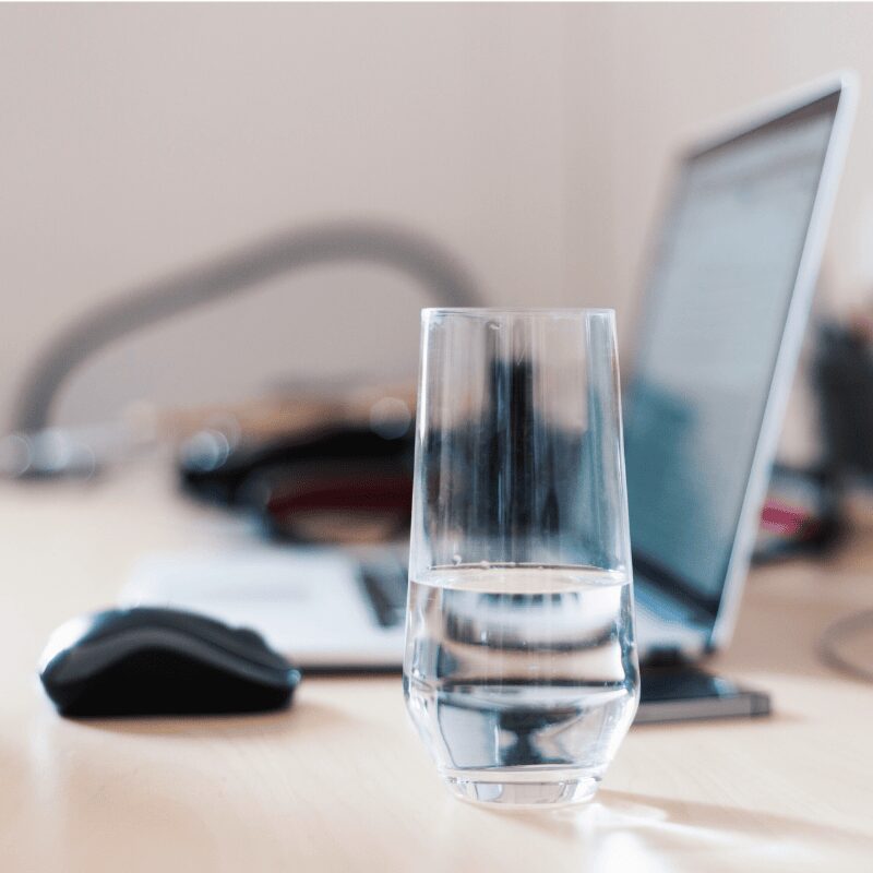 woman holding out glass of water in office