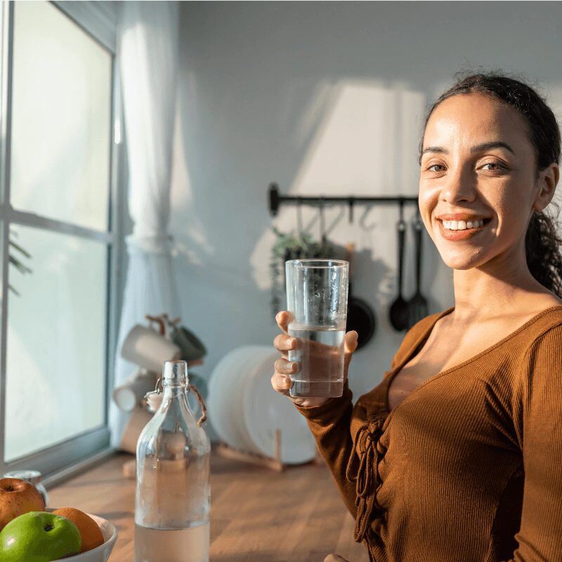 young-beautiful-latino-woman-holding-clean-water young Latina woman holding a glass of clean water at kitchen sink