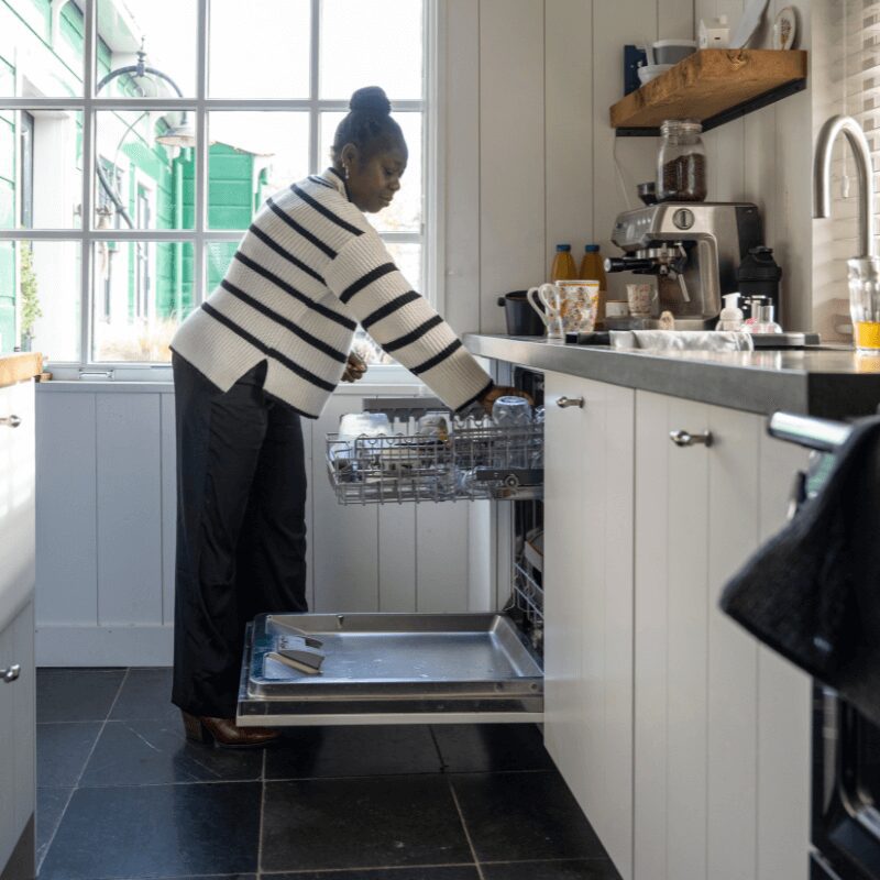 female-cleaning-her-kitchen-loading-the-dishwasher female cleaning her kitchen loading the dishwasher