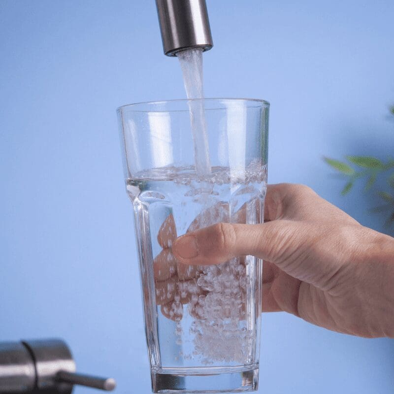 hand-holding-a-glass-and-filling-it-with-fresh water hand getting glass of water from tap
