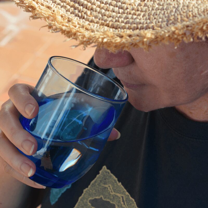 woman wearing large sun hat drinking water outdoors