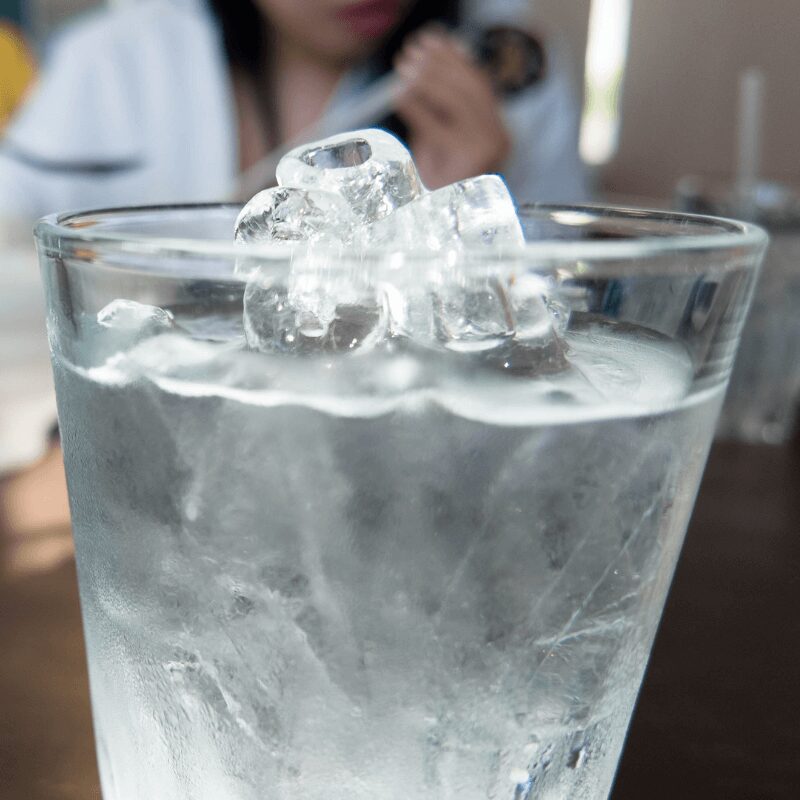front view of ice from ice machine melting against dark background
