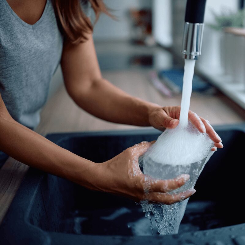 Close-up of a woman washing a drinking glass in soft water