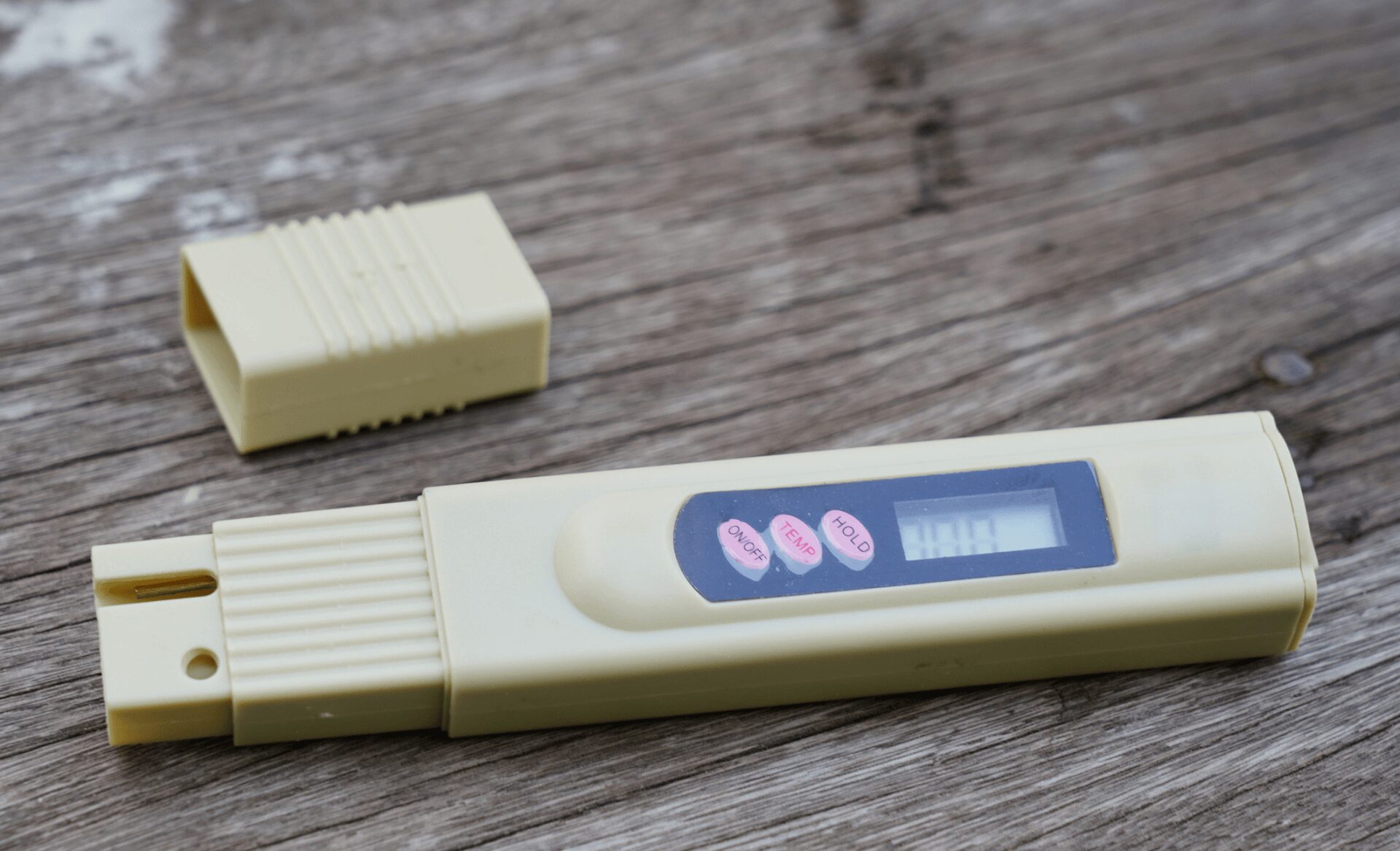 TDS Meter laying on a wood surface
