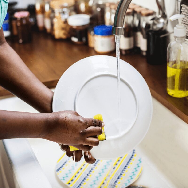 black woman washing a dish at the kitchen sink