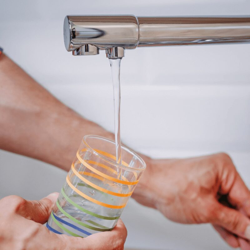 man pouring glass of water from the tap