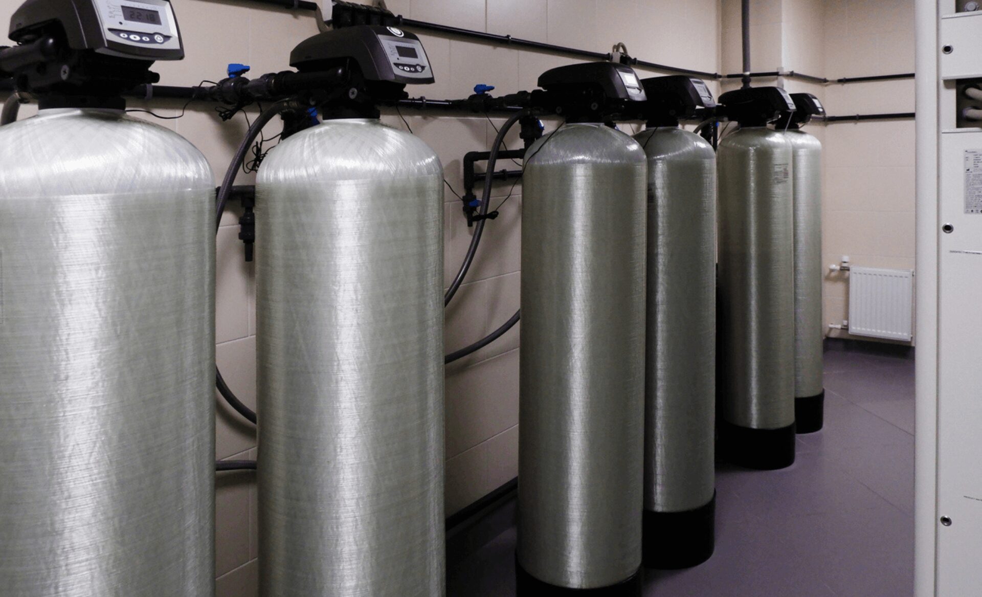 A row of commercial-grade water softeners in a utility area