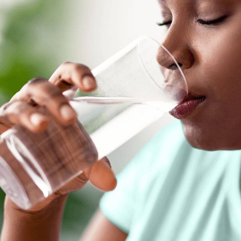 young black woman sipping water from a glass
