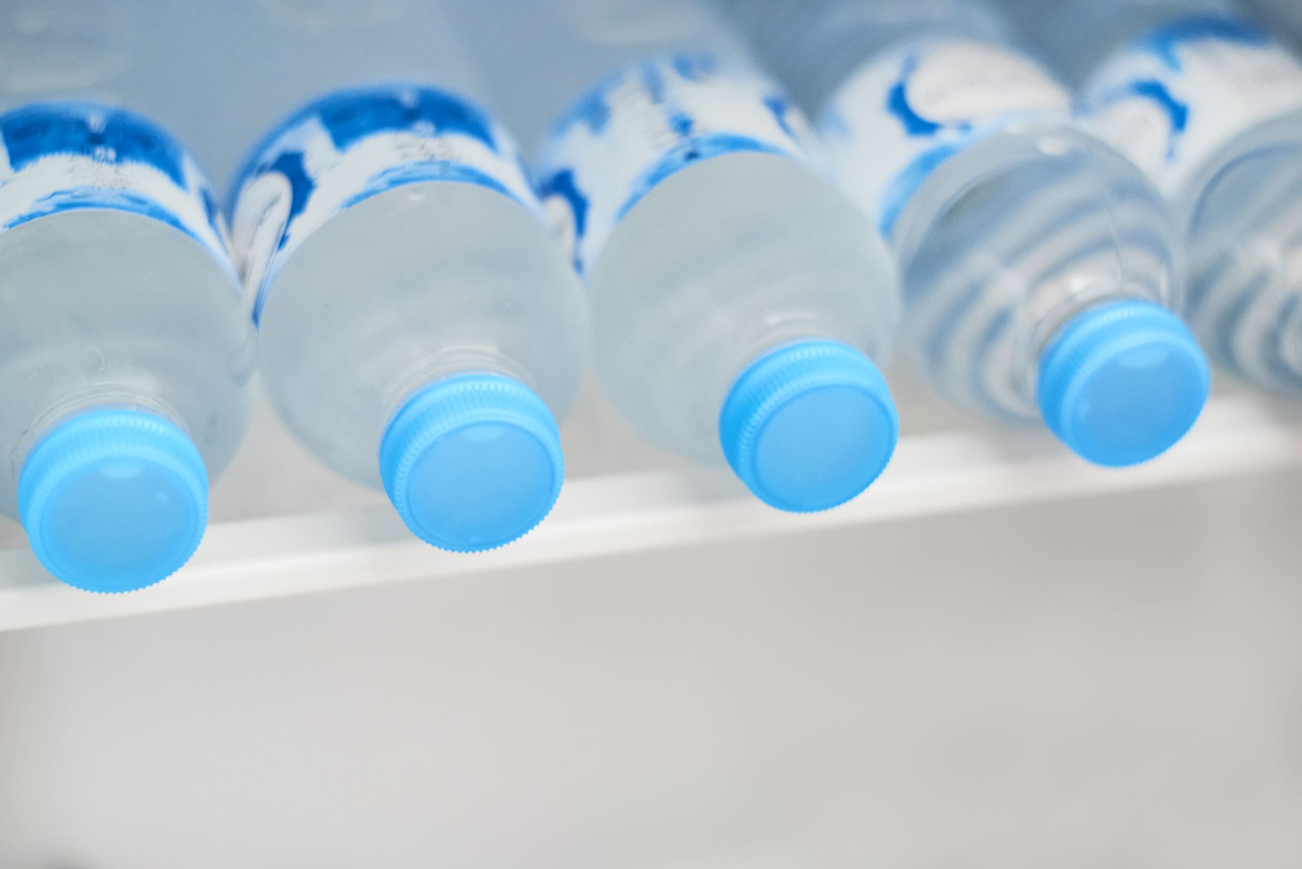 Up close picture of bottled waters lying down in the fridge.