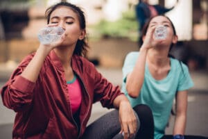two young women drinking from bottled waters