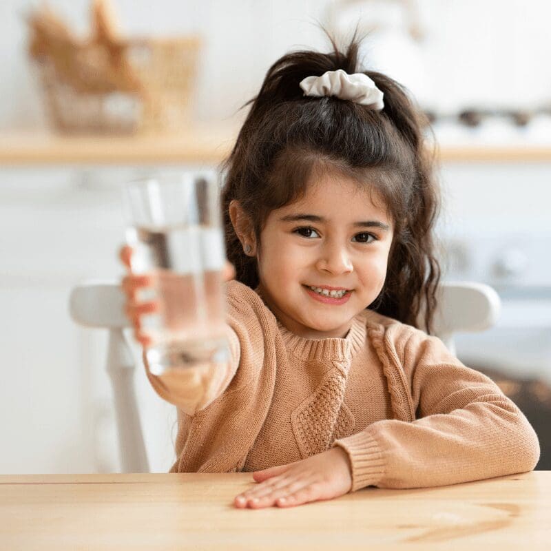 smiling-girl-holding-a-glass-of-water young girl holding out a glass of water to the camera