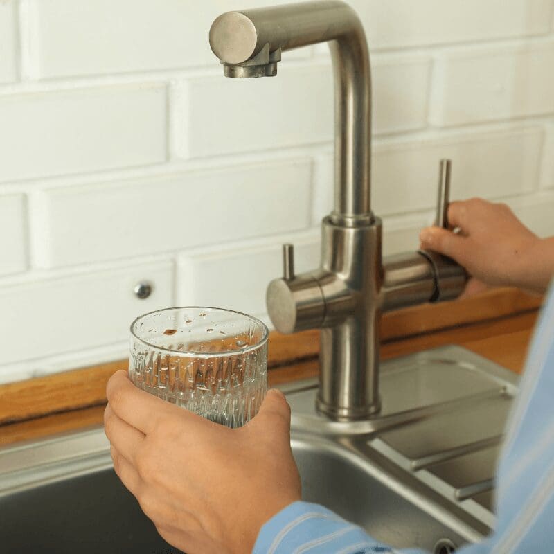 Close up of a hand filling a class of water at the kitchen sink